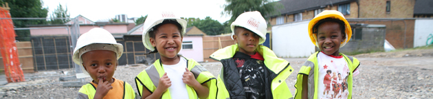 Four kids wearing yellow jackets and hard hats